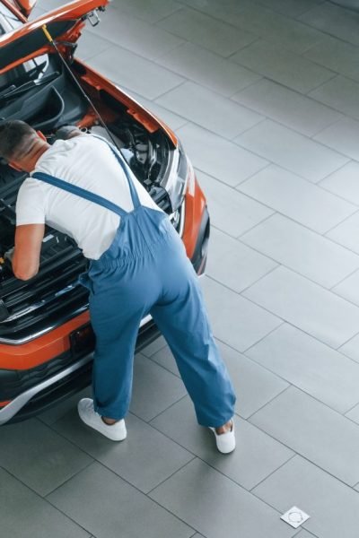 in-blue-uniform-man-is-repairing-broken-automobile-indoors.jpg